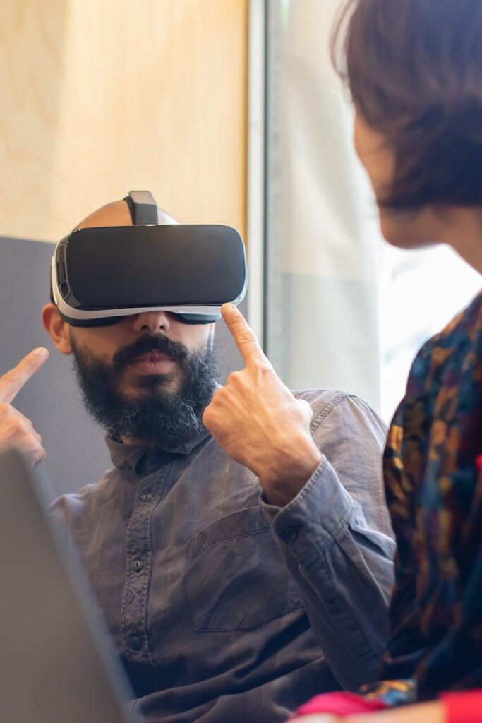 A man and woman explore virtual reality technology indoors with a laptop and VR goggles.